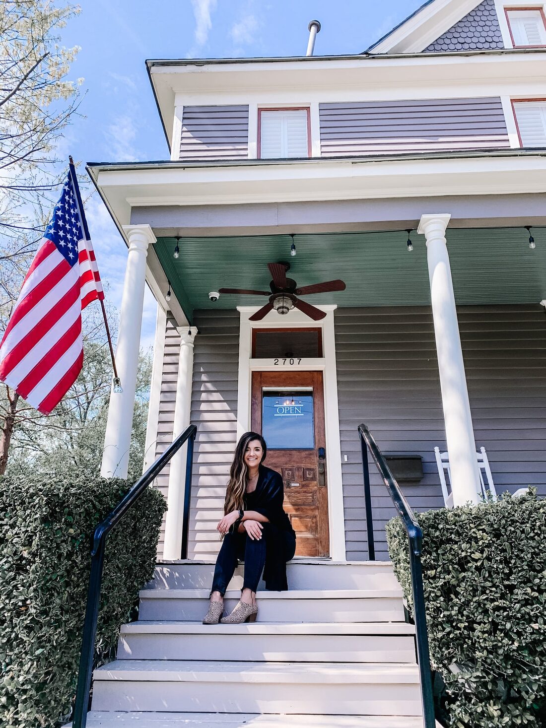 Kristy Gee, founder and brand strategist at KG Studio & Co., seated on the steps of a storefront